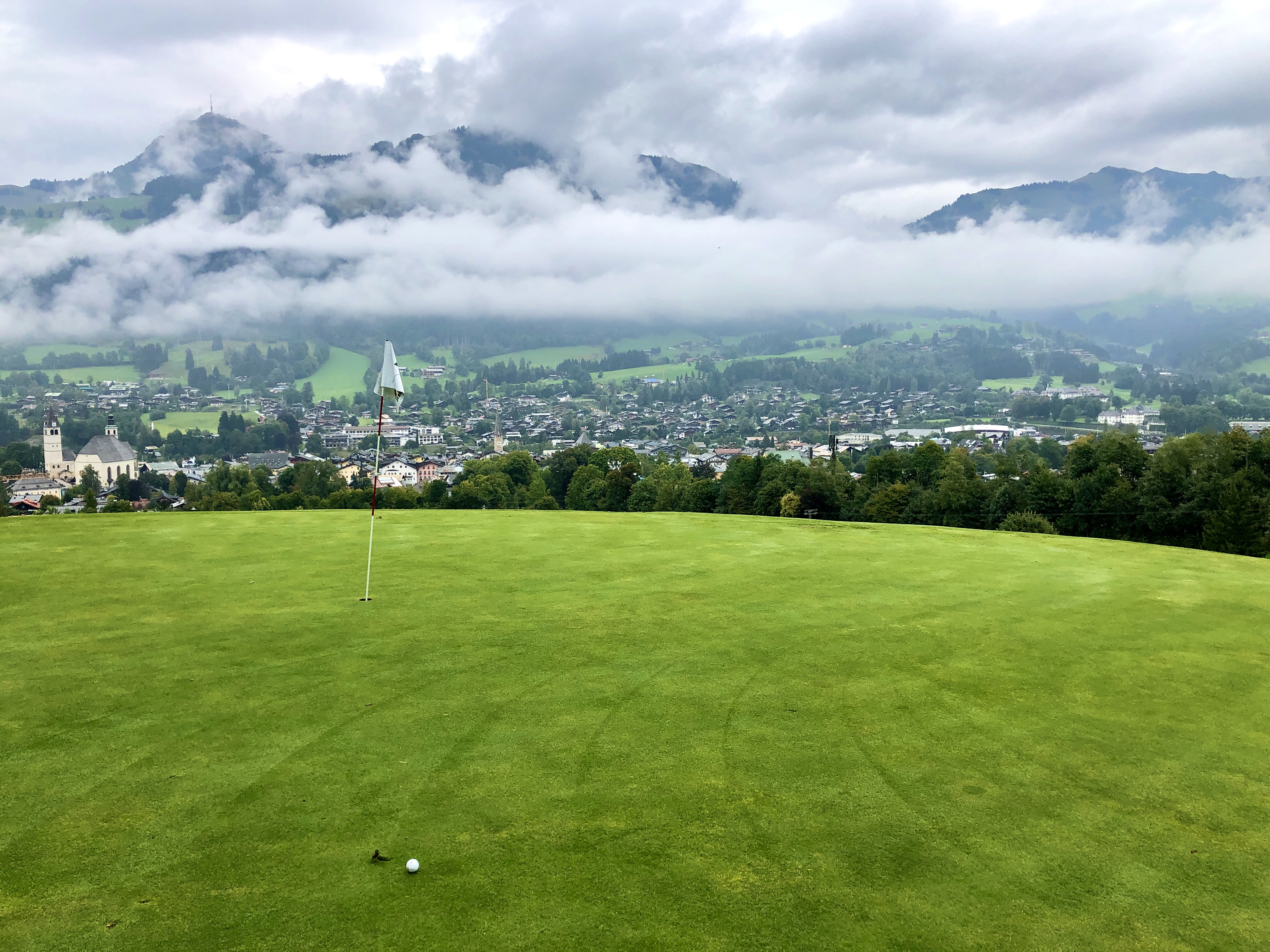 Blick vom Grün auf das Nebel umhüllte Kitzbühel